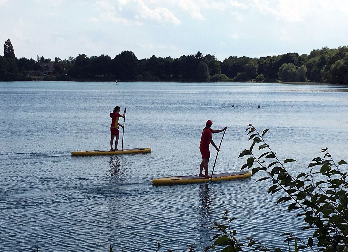 Rettungsschwimmer der DLRG auf SUP-Boards an einem Badesee