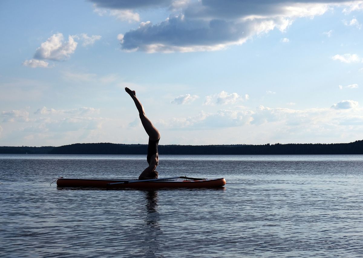 Kopfstand auf einem Board bei spiegelglattem Wasser – eine Position für Geübte